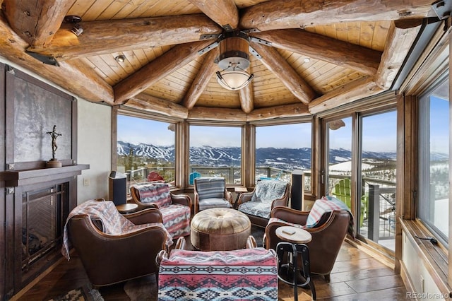 sunroom with a fireplace, beamed ceiling, wood ceiling, and a mountain view