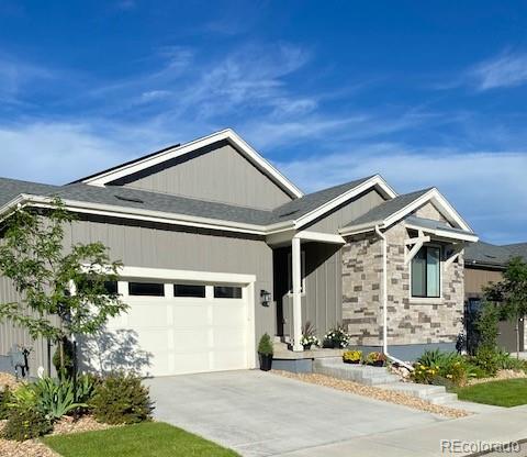 ranch-style house with an attached garage, stone siding, and driveway