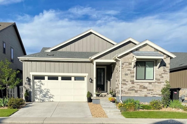 view of front of home with an attached garage, a shingled roof, concrete driveway, stone siding, and board and batten siding