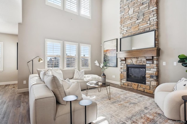 living room with a fireplace, a towering ceiling, dark hardwood / wood-style floors, and a wealth of natural light