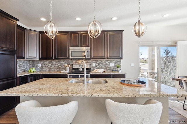 kitchen featuring decorative backsplash, appliances with stainless steel finishes, a kitchen island with sink, and pendant lighting