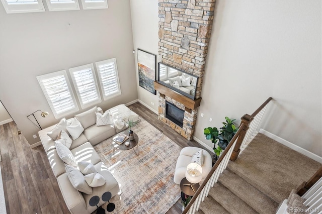 living room featuring a high ceiling, a stone fireplace, and dark wood-type flooring