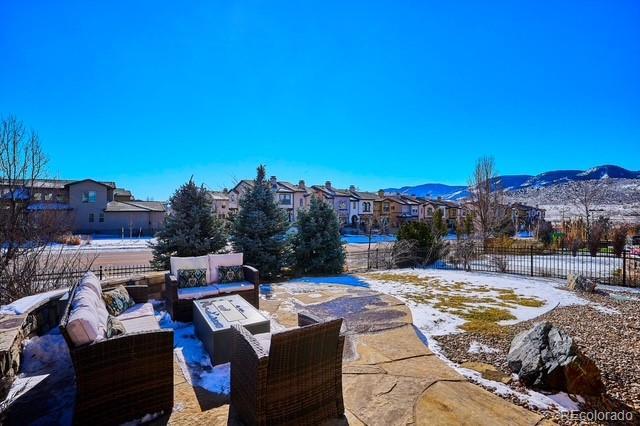 snow covered patio with a mountain view and an outdoor living space with a fire pit