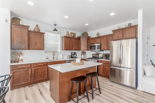 6400 S Ider St, Aurora, CO 80016 - kitchen featuring appliances with stainless steel finishes, light wood-type flooring, a breakfast bar, a kitchen island, and brown cabinetry
