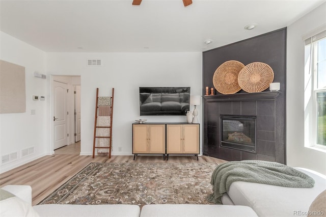 6400 S Ider St, Aurora, CO 80016 - living area with wood finished floors, a tiled fireplace, and a ceiling fan