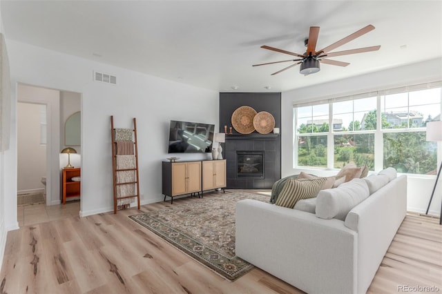 6400 S Ider St, Aurora, CO 80016 - living room featuring a fireplace, ceiling fan, and light wood-style floors
