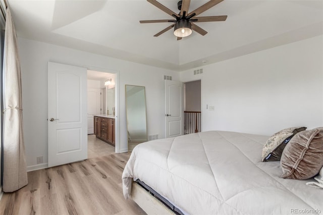 6400 S Ider St, Aurora, CO 80016 - bedroom with light wood-style flooring, connected bathroom, a raised ceiling, and a ceiling fan