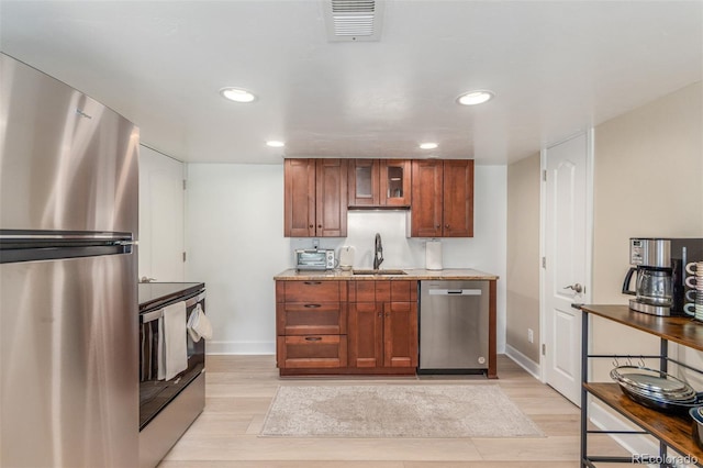 6400 S Ider St, Aurora, CO 80016 - kitchen featuring appliances with stainless steel finishes, light wood-style floors, glass insert cabinets, brown cabinets, and recessed lighting