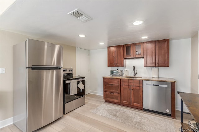 6400 S Ider St, Aurora, CO 80016 - kitchen with stainless steel appliances, recessed lighting, glass insert cabinets, brown cabinetry, and light stone counters