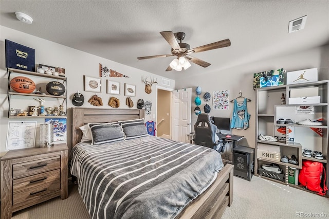 bedroom featuring visible vents, a textured ceiling, carpet, and a ceiling fan