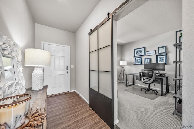 office area with baseboards, a barn door, and wood finished floors