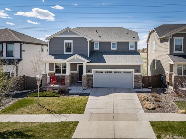 craftsman house with a garage, fence, stone siding, a shingled roof, and driveway