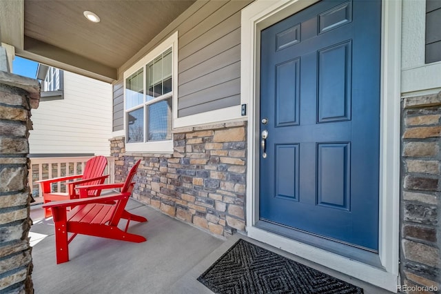 view of exterior entry featuring a porch and stone siding