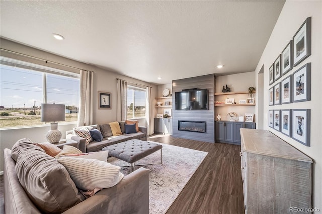 living area featuring dark wood-type flooring, recessed lighting, and a large fireplace