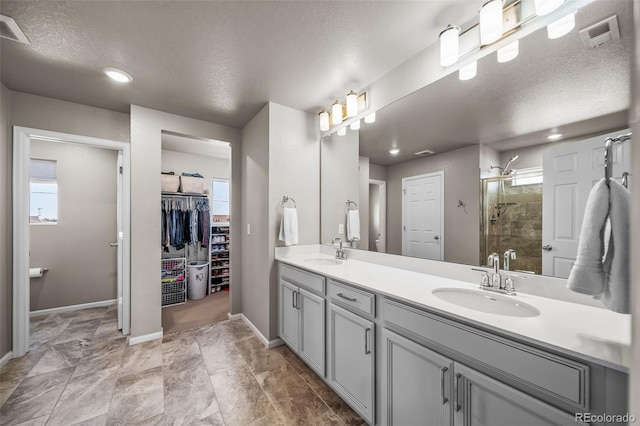 full bathroom featuring a stall shower, a textured ceiling, plenty of natural light, and a sink