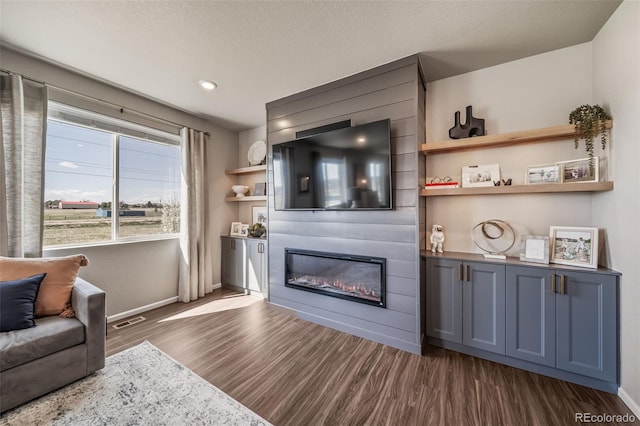 living room with baseboards, visible vents, a fireplace, and dark wood-type flooring