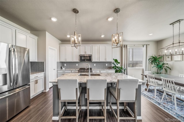 kitchen featuring a sink, appliances with stainless steel finishes, decorative backsplash, and a chandelier