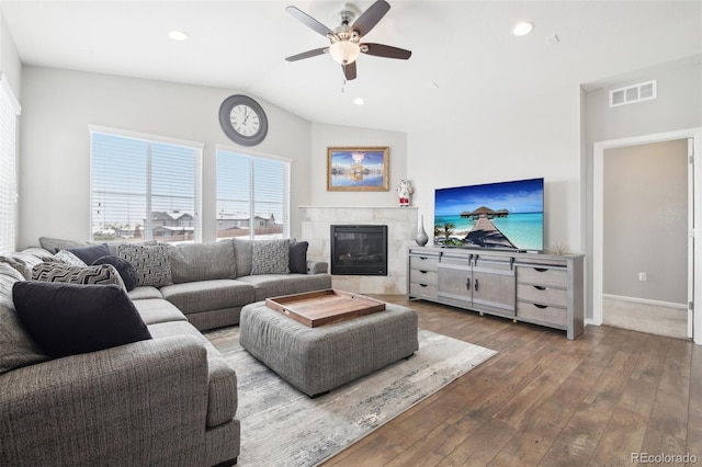 living room with ceiling fan, wood-type flooring, vaulted ceiling, and a tile fireplace