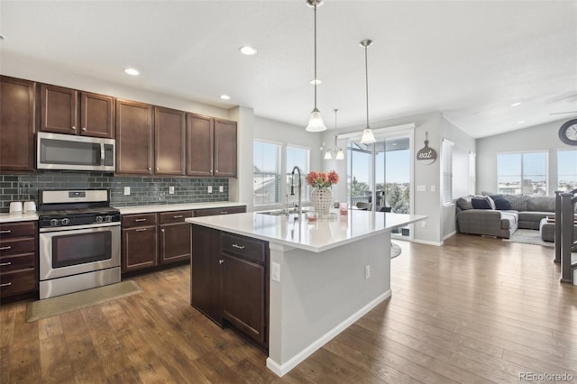 kitchen featuring sink, decorative light fixtures, dark hardwood / wood-style floors, stainless steel appliances, and a kitchen island with sink