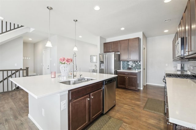 kitchen featuring pendant lighting, sink, appliances with stainless steel finishes, a kitchen island with sink, and dark hardwood / wood-style flooring