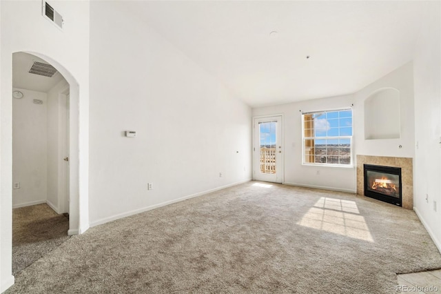 unfurnished living room featuring a tiled fireplace, high vaulted ceiling, and light carpet