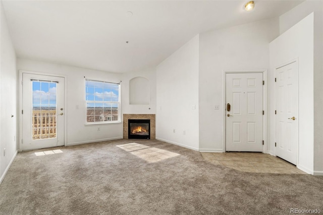 unfurnished living room with light colored carpet, lofted ceiling, and a tiled fireplace