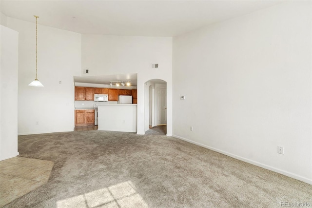 unfurnished living room featuring track lighting, high vaulted ceiling, and carpet flooring