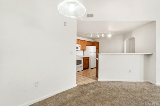 kitchen featuring white appliances, rail lighting, and light colored carpet