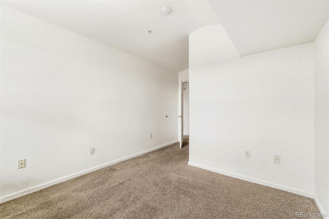 carpeted spare room featuring vaulted ceiling