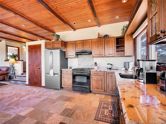 13012 S Wamblee Valley Rd, Conifer, CO 80433 - kitchen with black gas range oven, freestanding refrigerator, open shelves, wood ceiling with exposed beams, and under cabinet range hood