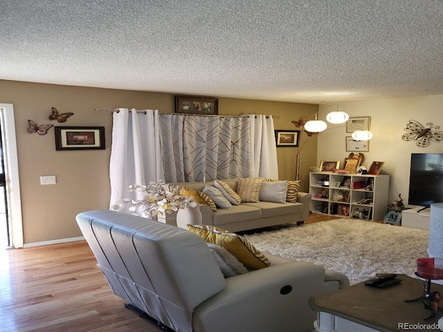 living room featuring light wood-type flooring and a textured ceiling