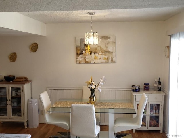 dining area with a chandelier, dark hardwood / wood-style floors, and a textured ceiling