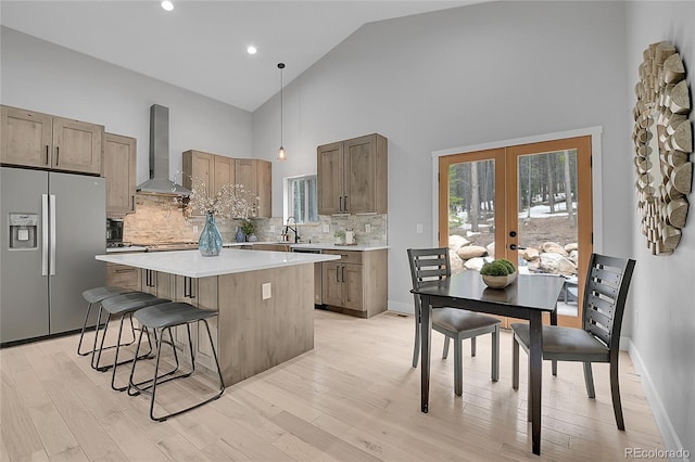 79 Beaver Rd, Idaho Springs, CO 80452 - kitchen featuring stainless steel fridge, wall chimney exhaust hood, high vaulted ceiling, a center island, and french doors