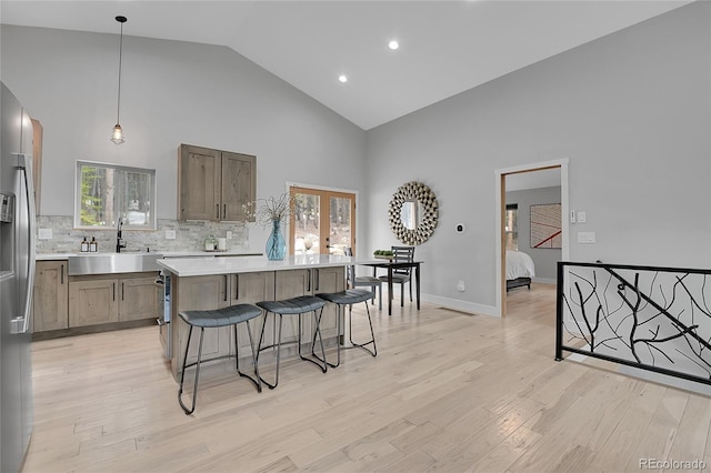 79 Beaver Rd, Idaho Springs, CO 80452 - kitchen with high vaulted ceiling, a sink, a kitchen bar, stainless steel fridge, and backsplash