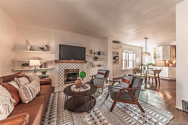 living room with visible vents, ornamental molding, a tile fireplace, an AC wall unit, and a textured ceiling