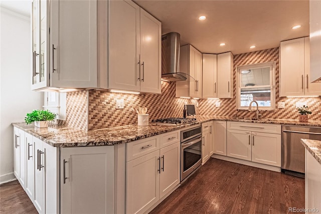 kitchen with white cabinets, stainless steel appliances, and wall chimney range hood