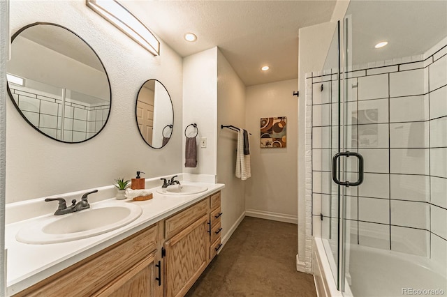 full bathroom featuring a shower with door, recessed lighting, double vanity, and a sink