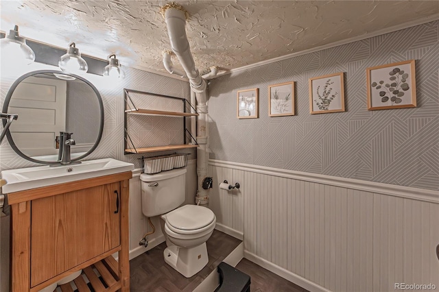 half bathroom with a wainscoted wall, toilet, vanity, and wood finished floors