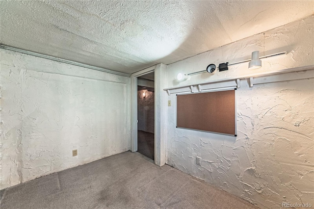 empty room featuring carpet flooring, a textured ceiling, and a textured wall