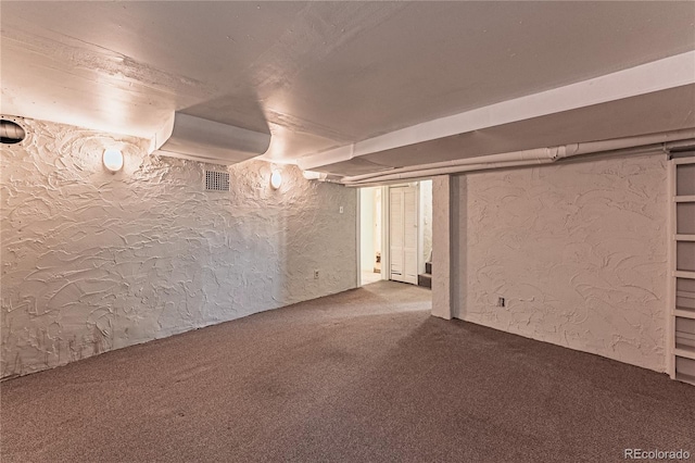 below grade area with visible vents, carpet, and a textured wall