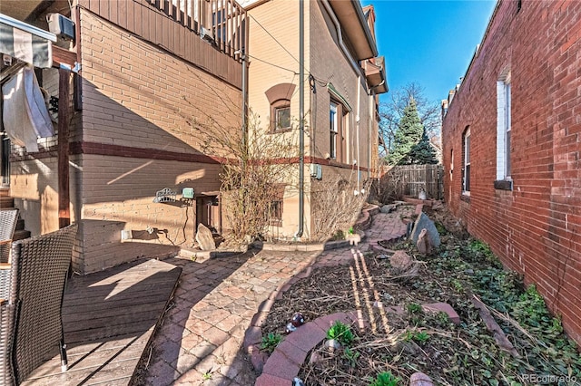 view of property exterior featuring fence and brick siding