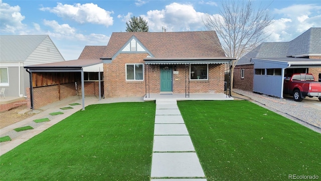 view of front facade featuring a shingled roof, a front yard, and brick siding