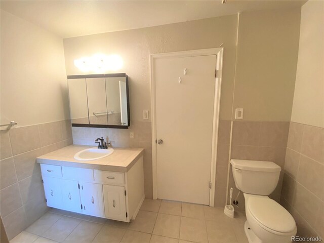 bathroom with tile patterned flooring, vanity, tile walls, and toilet