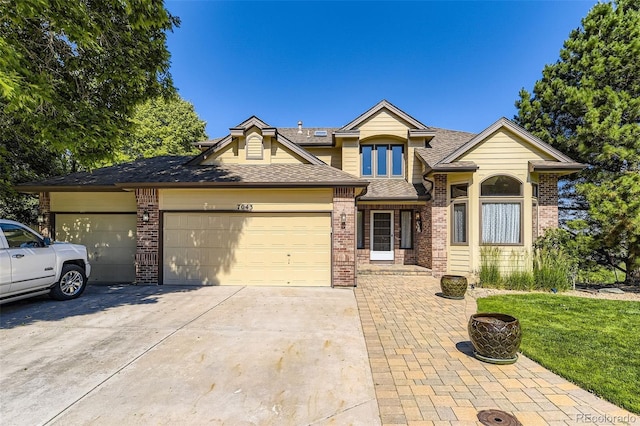 7043 S Owens Way, Littleton, CO 80127 - view of front of home featuring a garage, brick siding, concrete driveway, and a shingled roof