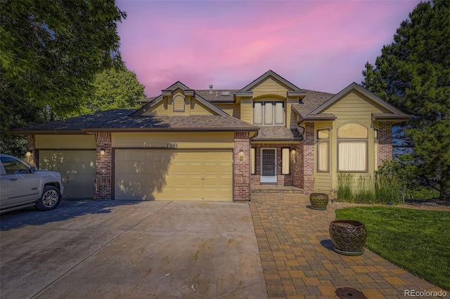 7043 S Owens Way, Littleton, CO 80127 - view of front facade featuring concrete driveway, an attached garage, brick siding, and a shingled roof