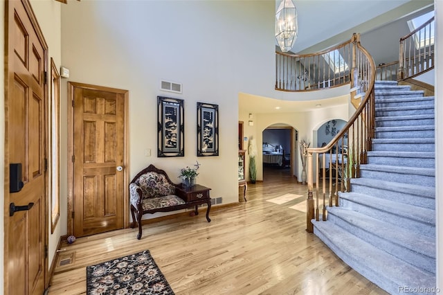 7043 S Owens Way, Littleton, CO 80127 - foyer entrance featuring arched walkways, a towering ceiling, wood finished floors, stairs, and a chandelier