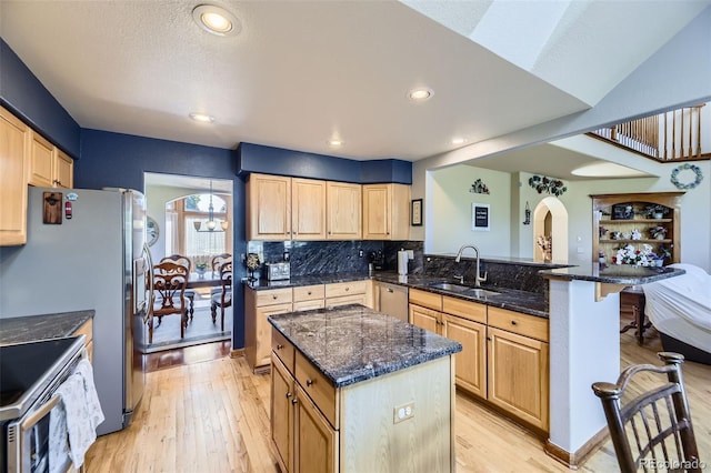 7043 S Owens Way, Littleton, CO 80127 - kitchen with light brown cabinetry, arched walkways, a peninsula, stainless steel appliances, and recessed lighting