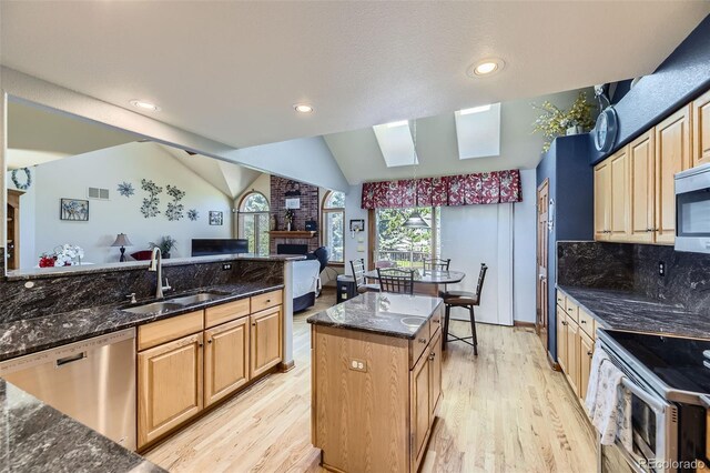 7043 S Owens Way, Littleton, CO 80127 - kitchen with stainless steel appliances, light wood-style floors, a fireplace, lofted ceiling, and a skylight
