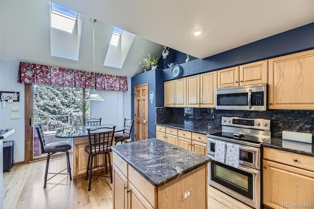 7043 S Owens Way, Littleton, CO 80127 - kitchen with appliances with stainless steel finishes, a skylight, light brown cabinets, a kitchen island, and backsplash