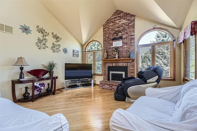7043 S Owens Way, Littleton, CO 80127 - living area with wood finished floors, healthy amount of natural light, high vaulted ceiling, and a fireplace